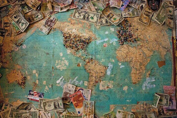 World map covered in pins and money.